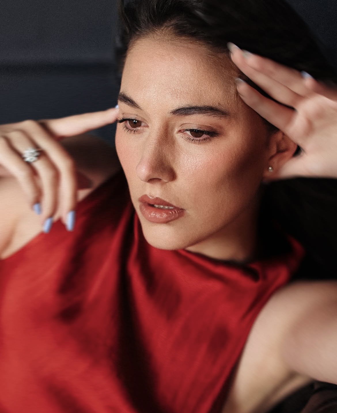 Close-up portrait in red fabric with blue nails