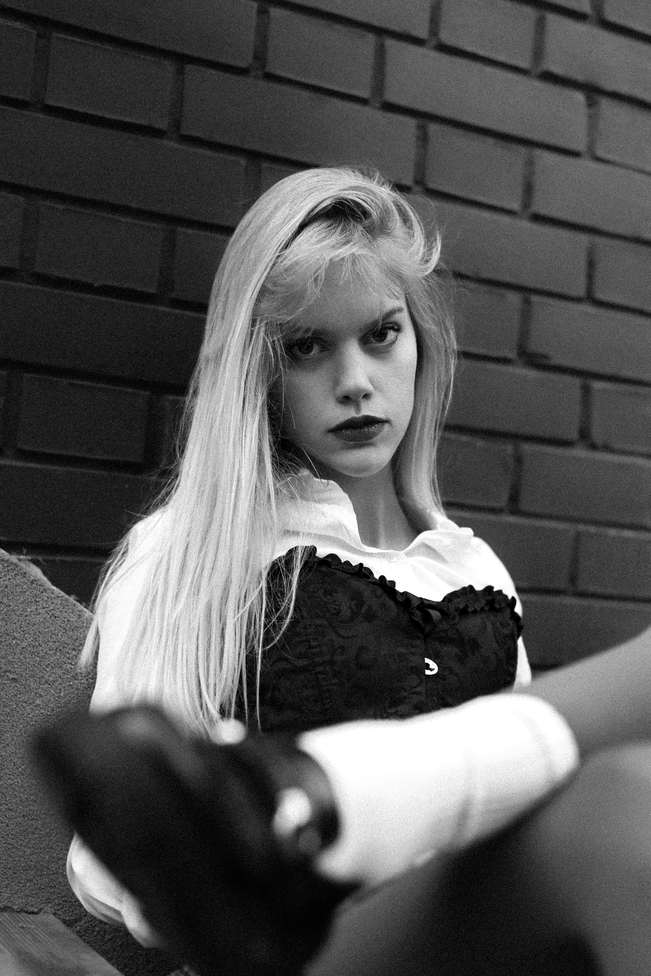 Black-and-white portrait of a blonde model against a brick wall