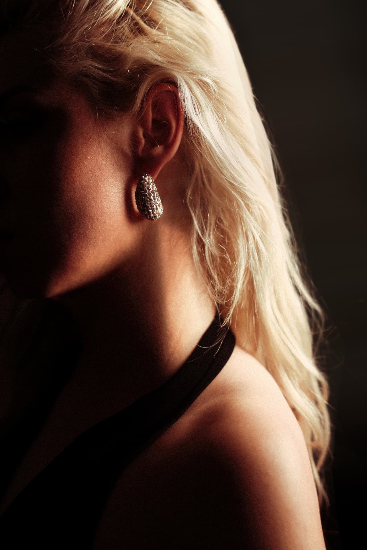 Blonde profile with crystal earring in warm light