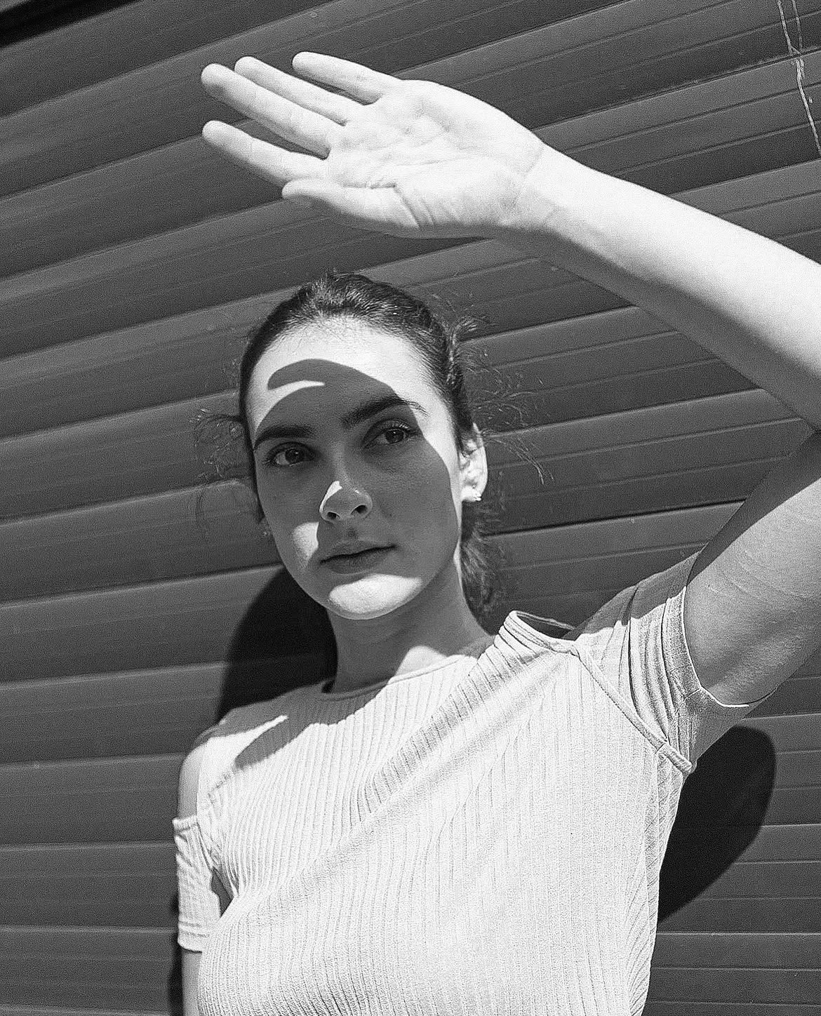 Black-and-white brunette with hand raised against slats