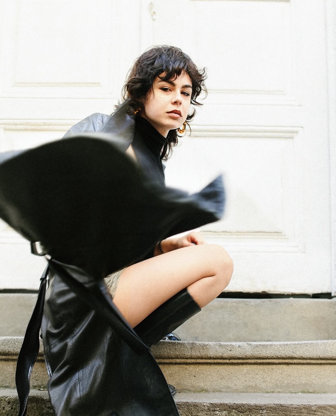 Street portrait of a seated model in black with curly hair