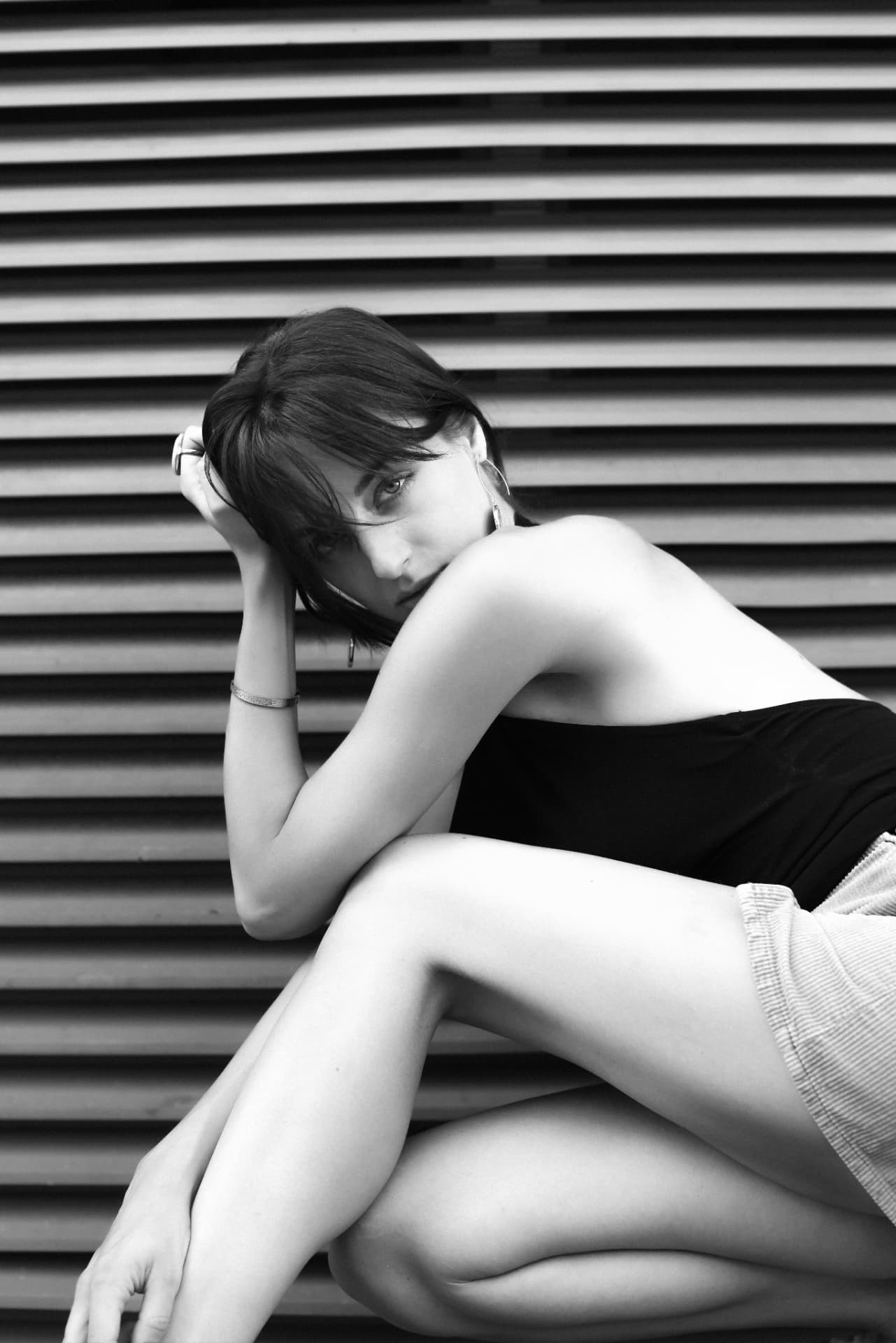 Brunette reclining against slatted metal wall