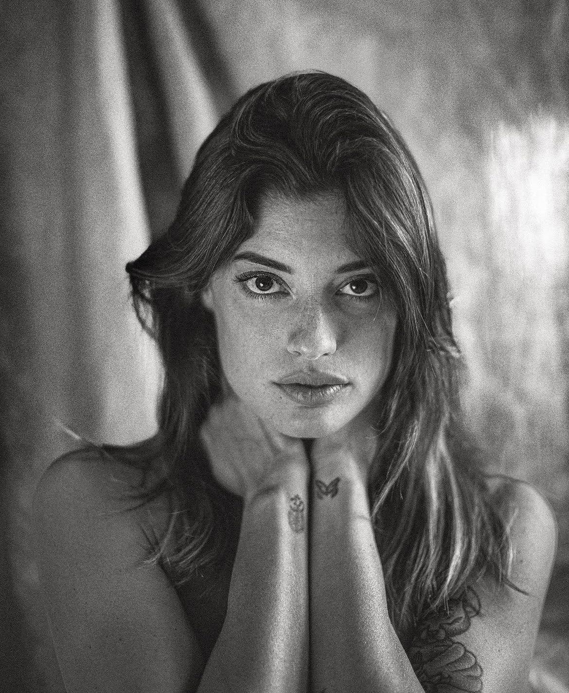 Black-and-white portrait with hands near the chin