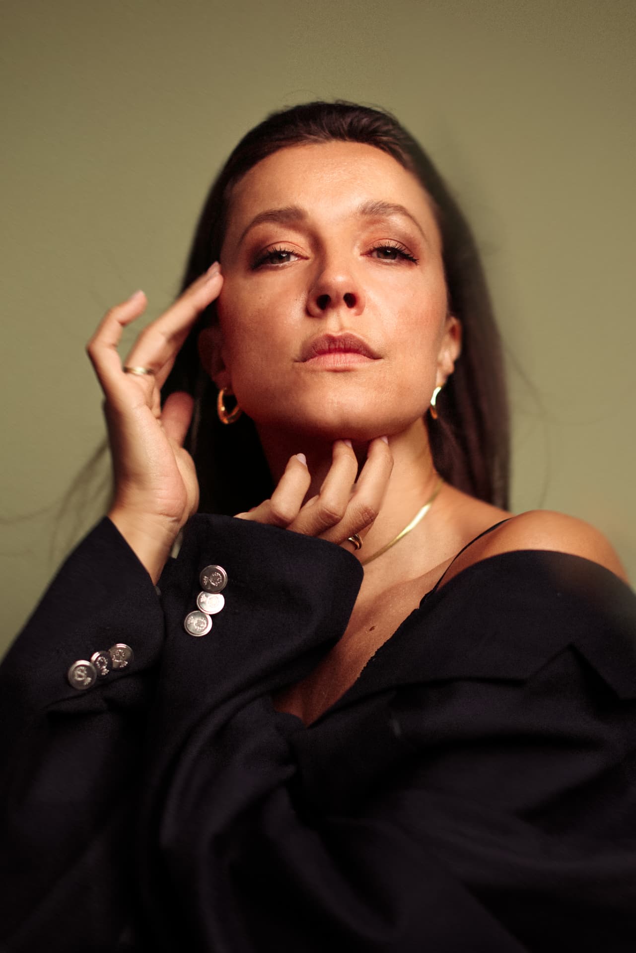 Close portrait in black blazer against olive wall