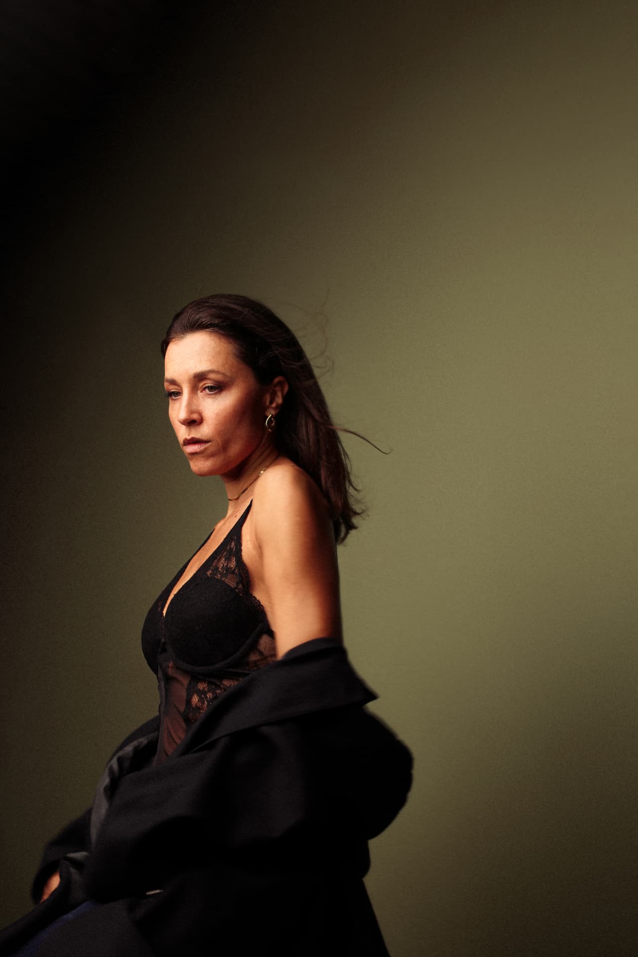 Profile portrait in black blazer, olive backdrop