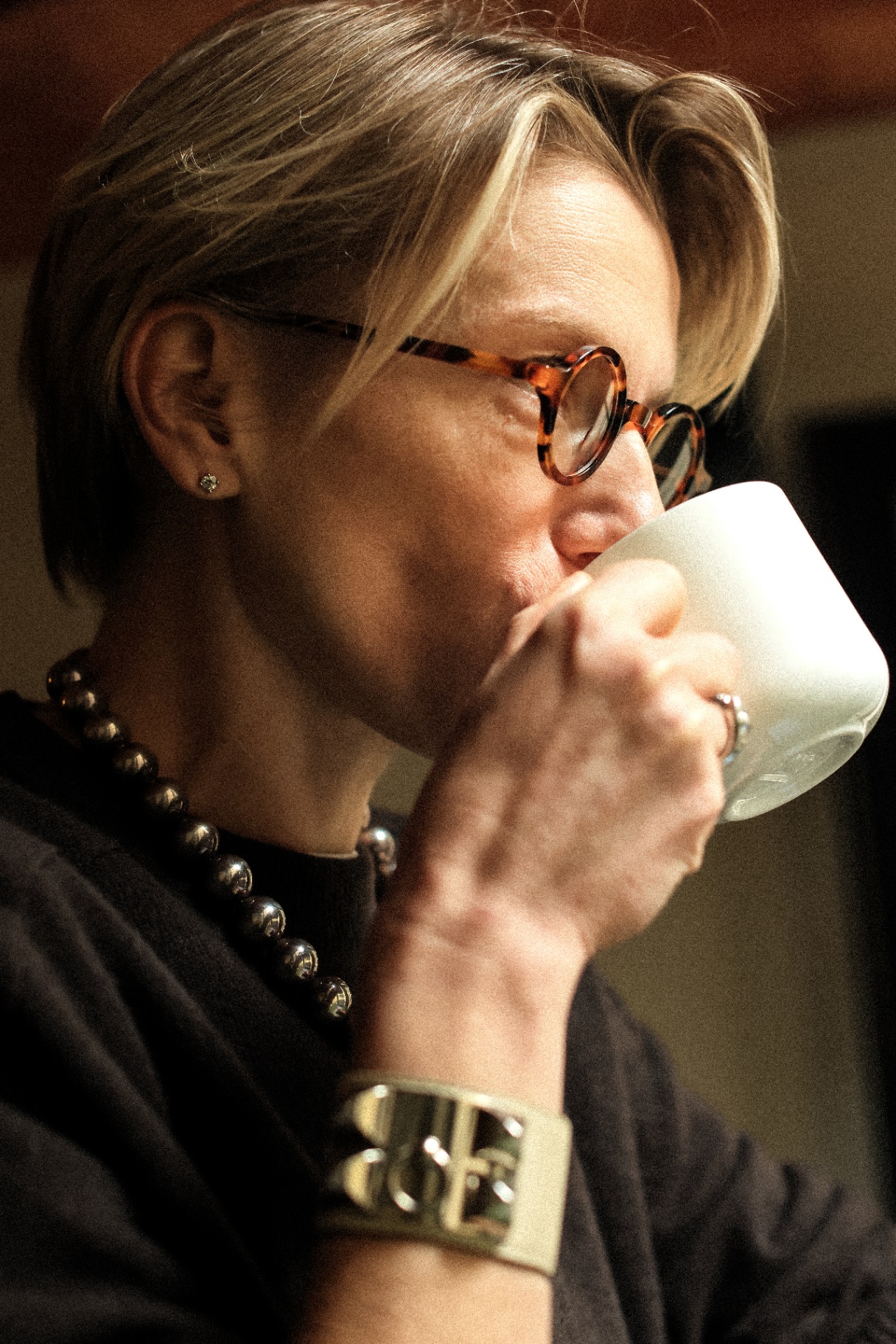 Blonde model with tortoiseshell glasses drinking from a cup
